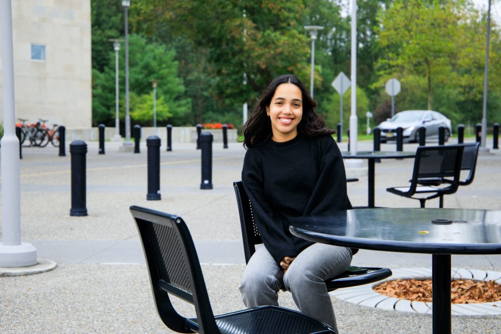 Abigail Jones sits outside at a table on the campus of Rowan University. 