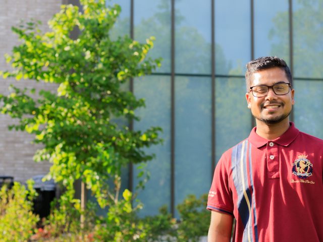 Pintu stands outside an academic building.