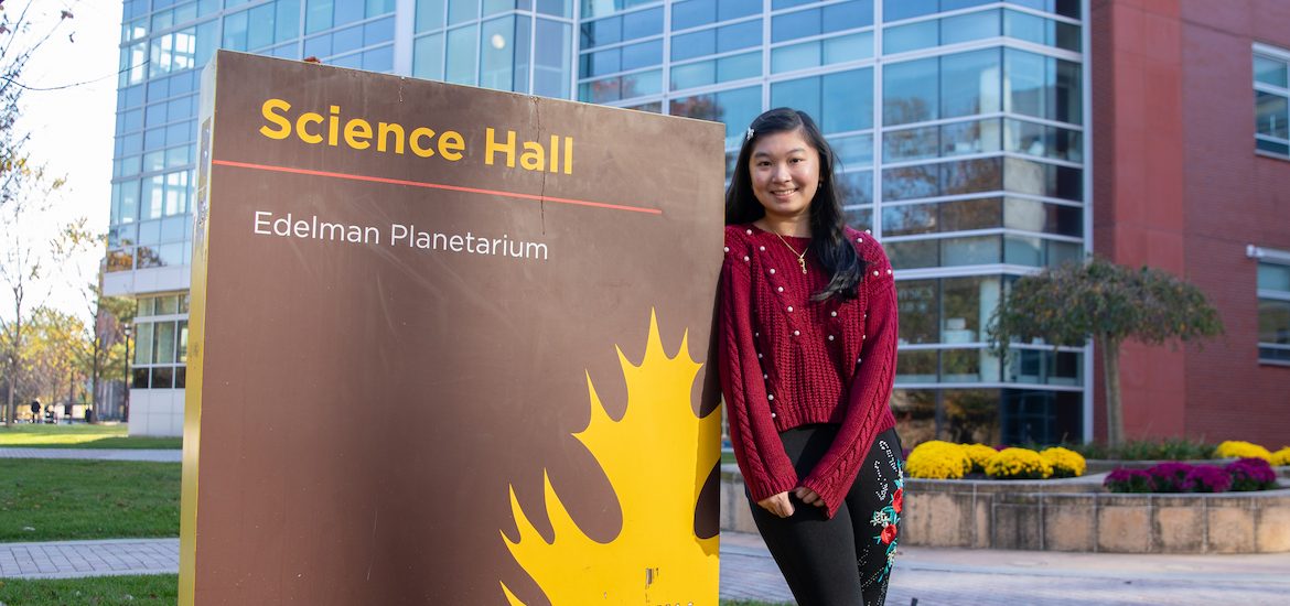 Cindy stands next to the Science Hall sign.