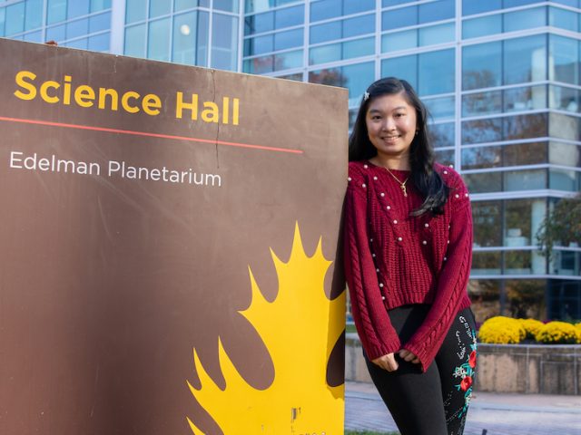 Cindy stands next to the Science Hall sign.