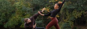 Two dancers in mid-pose outdoors.