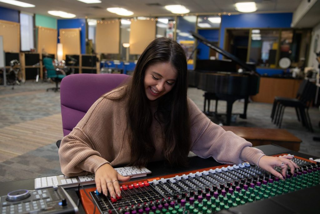 Alyssa bows her head down while smiling, working on a sound board. 