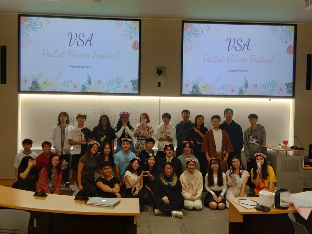 A group photo of all the VSA students sitting for a portrait, with their welcome PowerPoint behind them. 