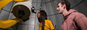 Two students peer into a giant telescope in the planetarium.