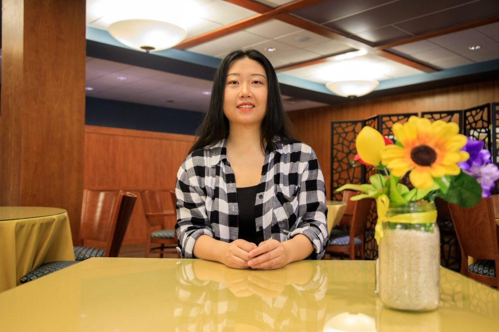 Evangeline Li sitting at a table with her hands together and flowers to the right of her