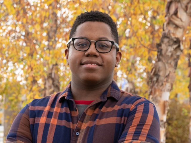 Sedrick standing outside with leaves and trees in the background