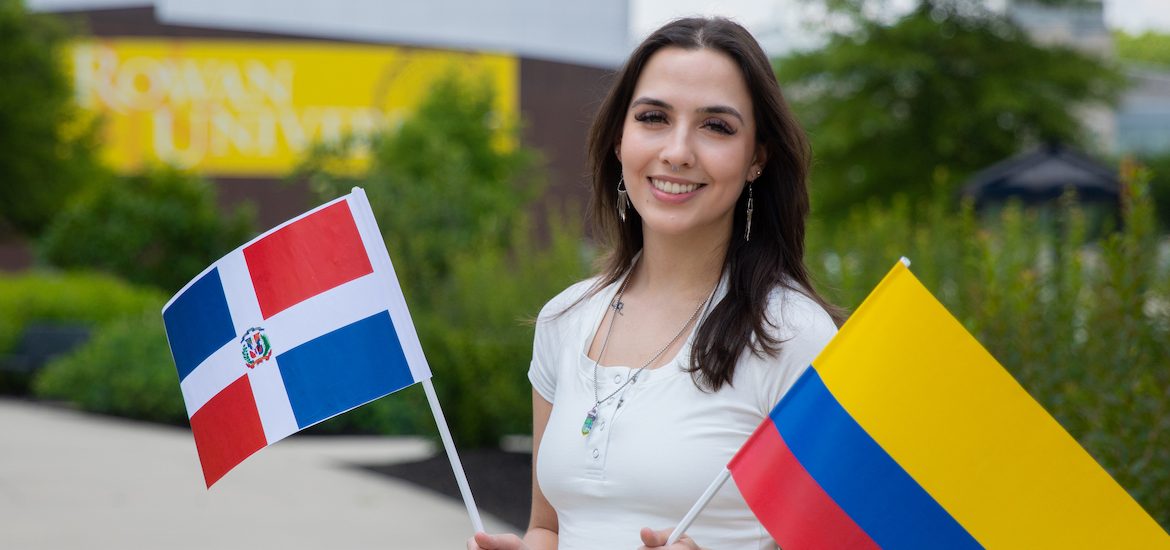 Rowan University's Bonnie Williams standing outside holding two flags