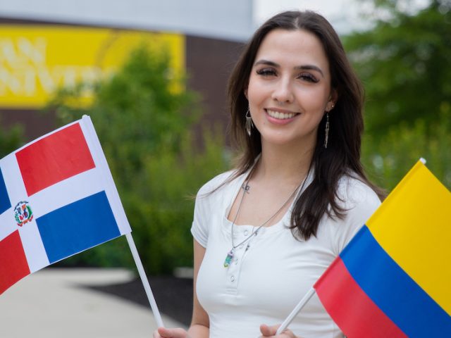 Rowan University's Bonnie Williams standing outside holding two flags