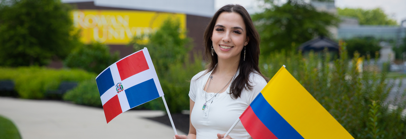 Rowan University's Bonnie Williams standing outside holding two flags