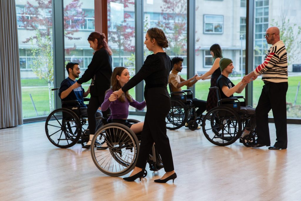 American DanceWheels ballroom class inside of the Wilson Dance Studios. Pictured are able-bodied dancers, and dancers using wheelchairs partnering together.