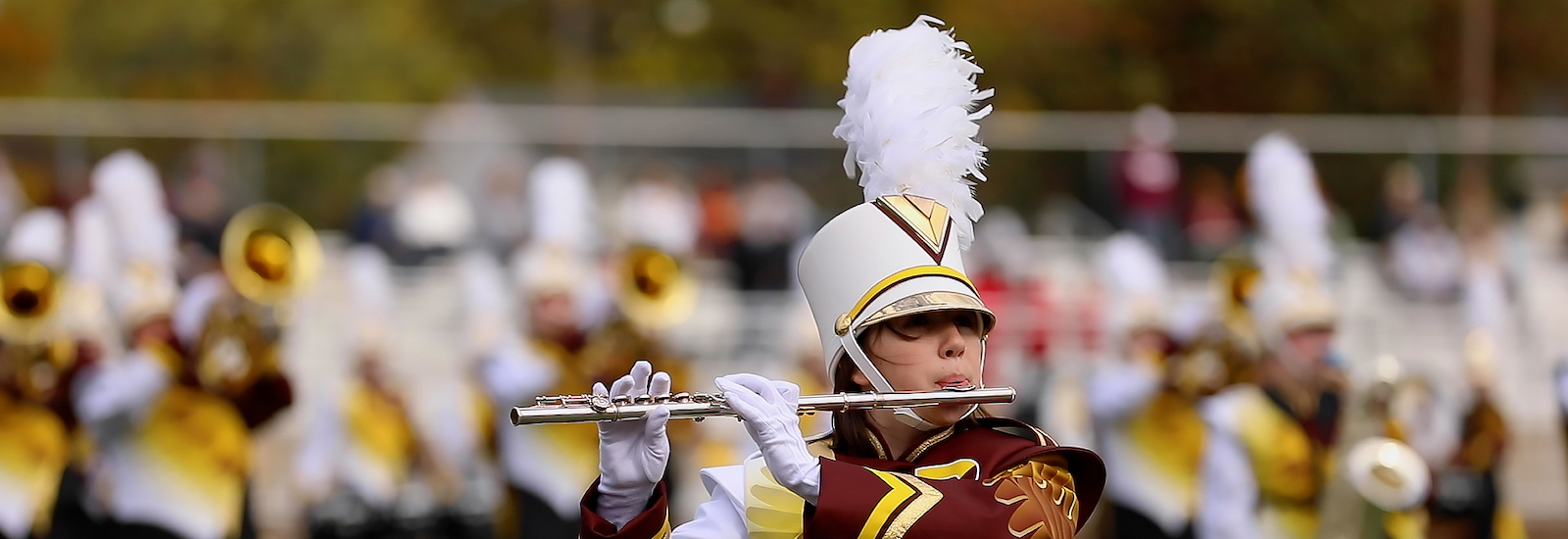A close up of marching band members in uniform playing instruments duirng a game.