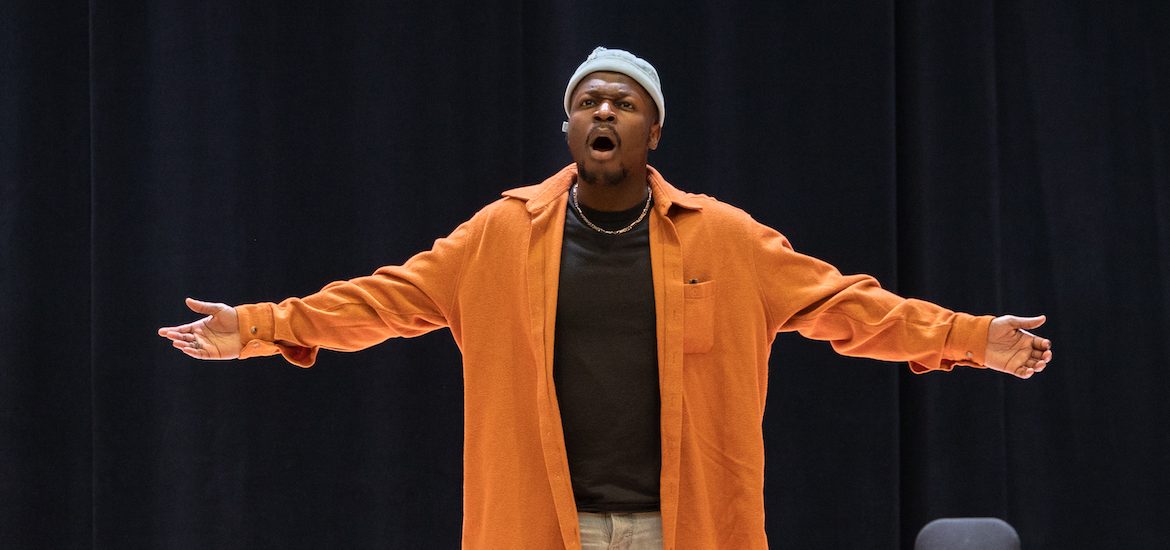 Vocal performance major Moses at Rowan University singing on the Boyd Concert Hall stage. He is seen with his arms out.