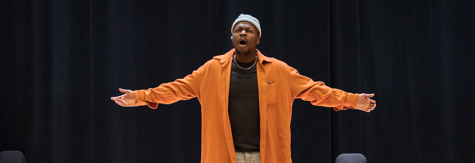 Vocal performance major Moses at Rowan University singing on the Boyd Concert Hall stage. He is seen with his arms out.