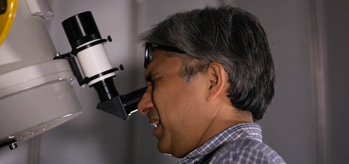 Professor Erick Guerra looking at a telescope on the roof of Science Hall.