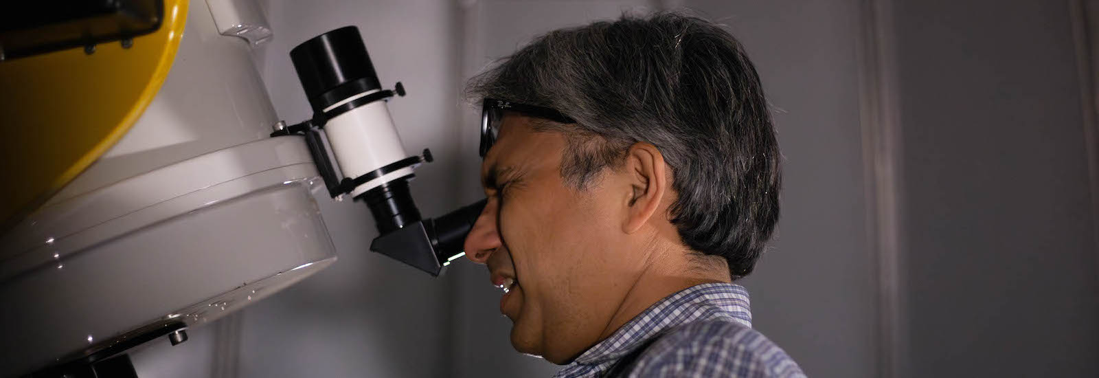 Professor Erick Guerra looking at a telescope on the roof of Science Hall.