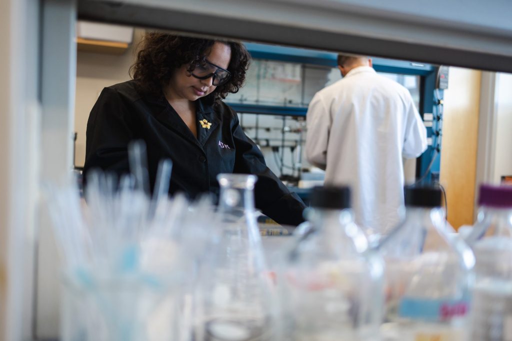 A biological sciences major works in the lab, looking down at a lab bench with empty glass beakers in front of her. 