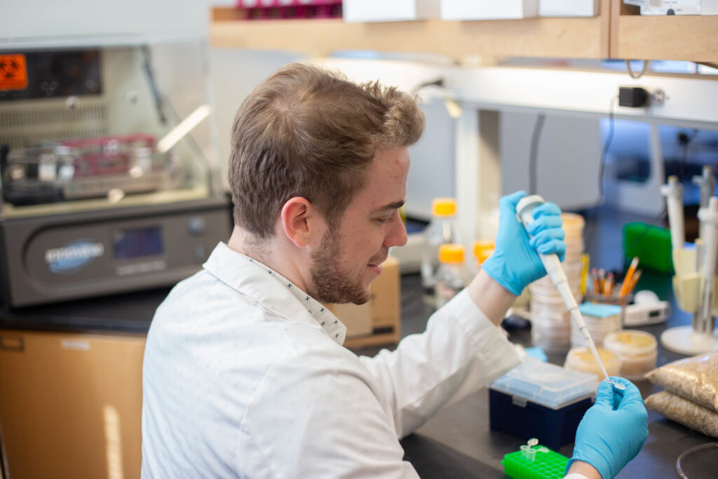 Rowan University biological sciences major Brian Libby uses a pipette in a lab. 