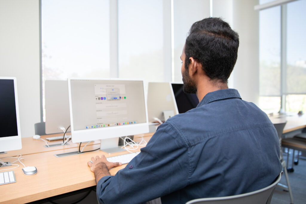 A man sitting at a desk with a computer monitor.