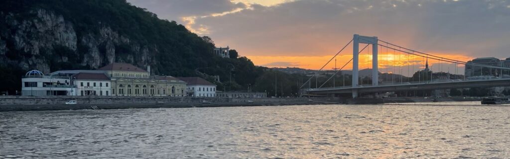 A sunset in a river with a bridge