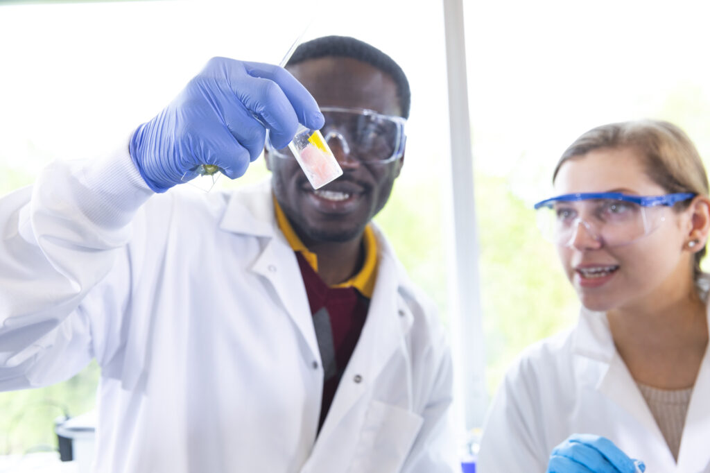 A scientist studies what's in a bottle as another student scientist looks on. 