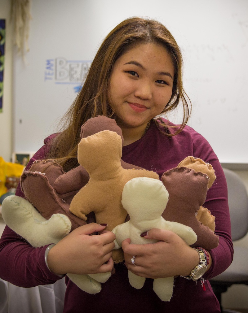 A student holds stitched stuffed animals for charity. 