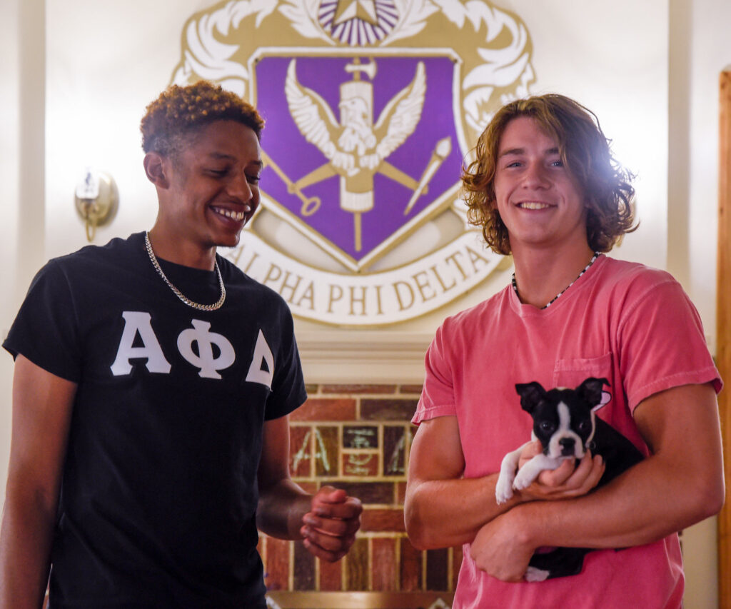 Two members of Greek Life at Rowan University in Alpha Phi Delta Fraternity hang out with their puppy. 