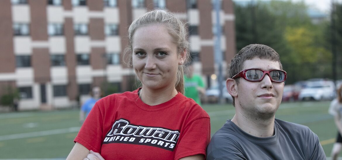 Two students stand shoulder to shoulder on an athletic field at Rowan University.