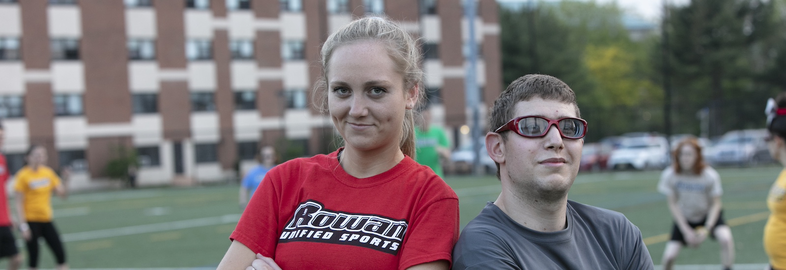 Two students stand shoulder to shoulder on an athletic field at Rowan University.