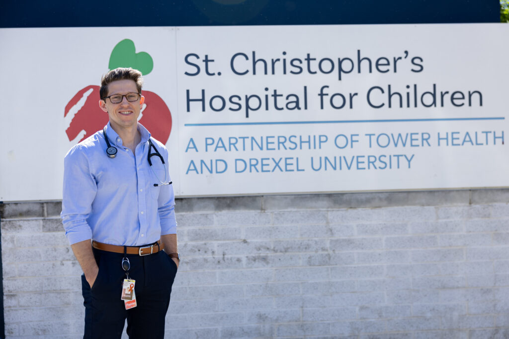 Richie stands outside of St. Christopher's sign at work. 