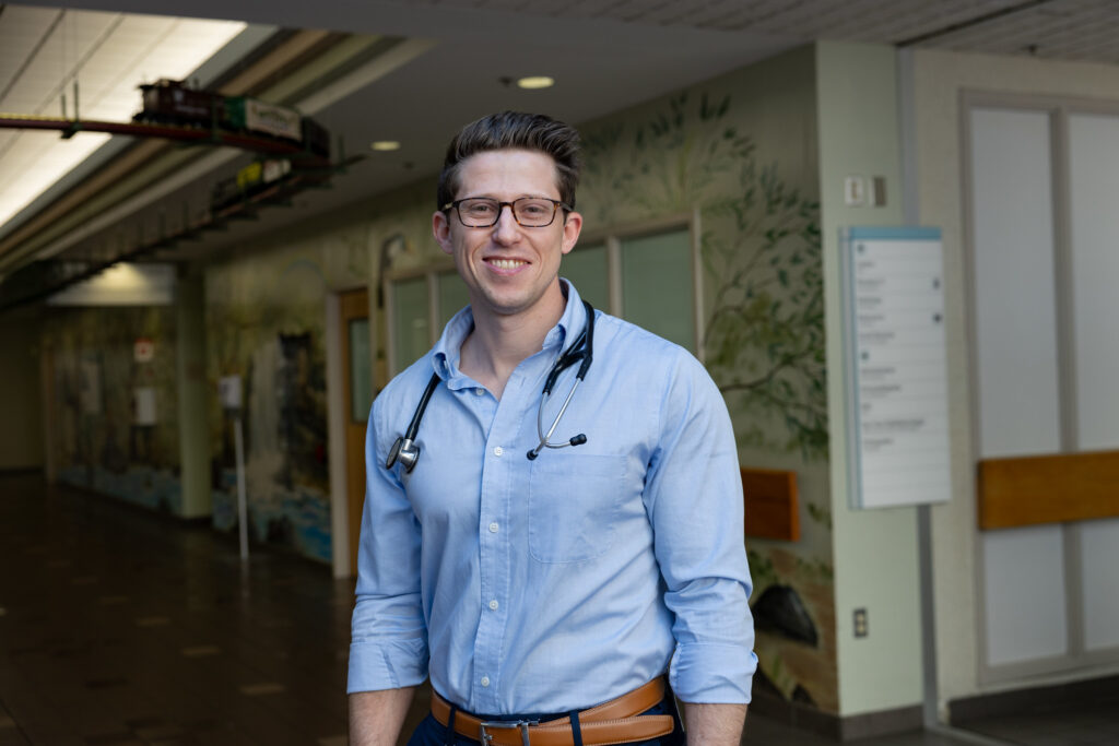 Cooper Medical School of Rowan University graduate Richie Suarez stands for a formal portrait, with a stethoscope around his neck. 