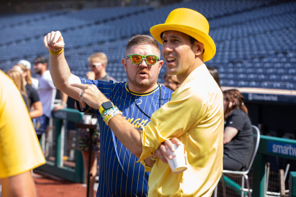 Rowan University alumnus and Savannah Bananas Matt Graifer talking with Jesse Cole, who is wearing an all yellow suit and hat.