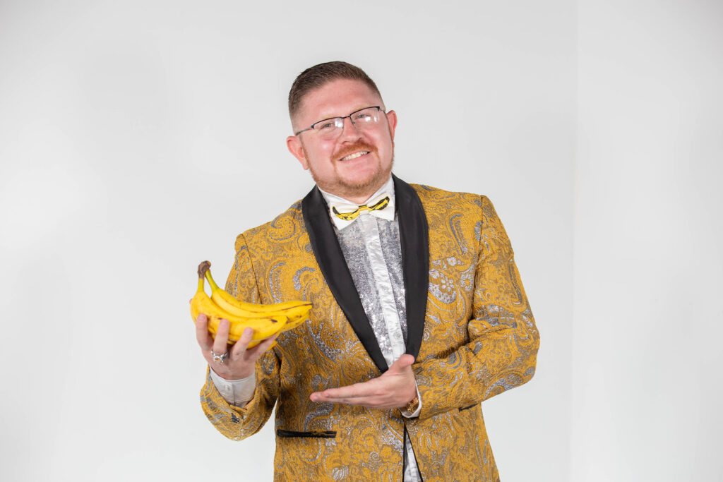 Rowan University alumnus and Savannah Bananas Matt Graifer dressed in a gold and silver tux, holding bananas. 