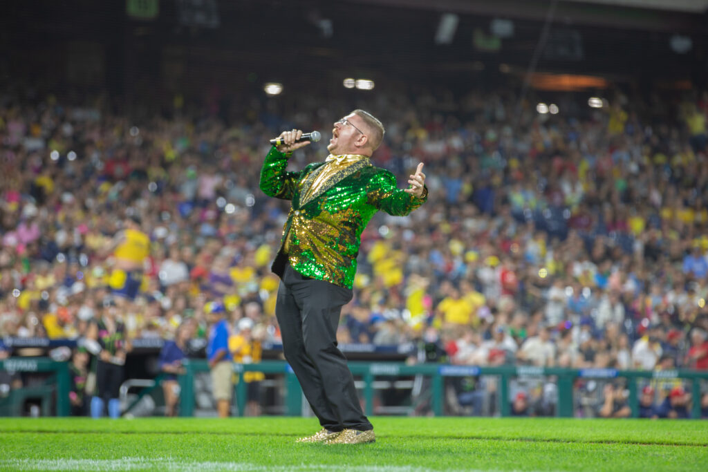 Rowan University alumnus and Savannah Bananas Matt Graifer wearing a green and gold tux, announcing out on the field.