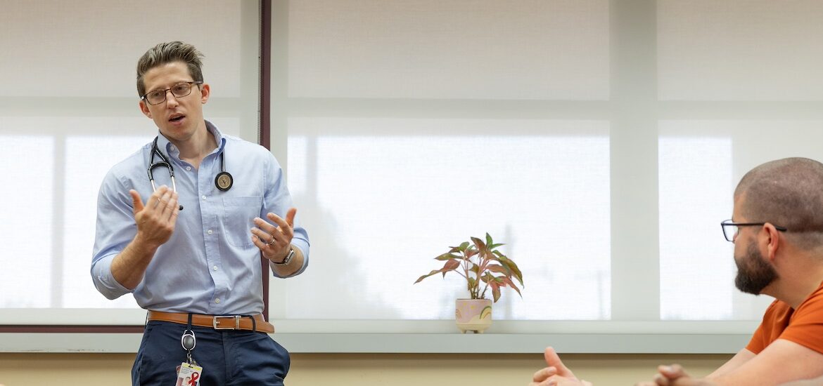 Cooper Medical School of Rowan University graduate Richie Suarez leads a discussion in a conference room.