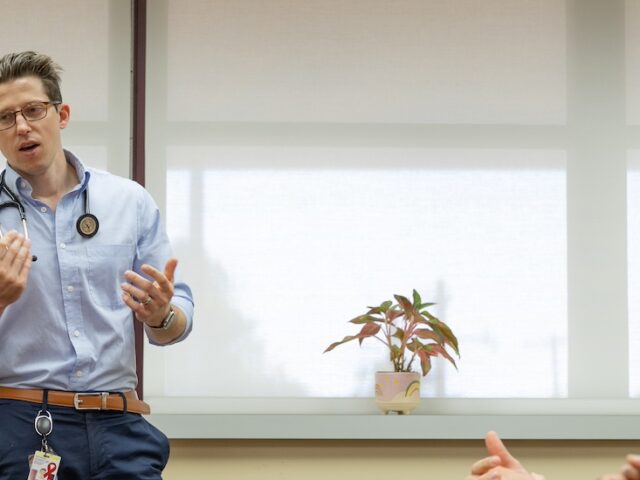 Cooper Medical School of Rowan University graduate Richie Suarez leads a discussion in a conference room.