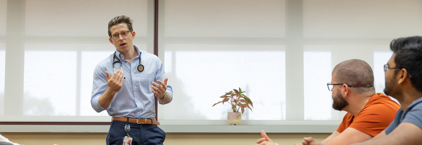 Cooper Medical School of Rowan University graduate Richie Suarez leads a discussion in a conference room.