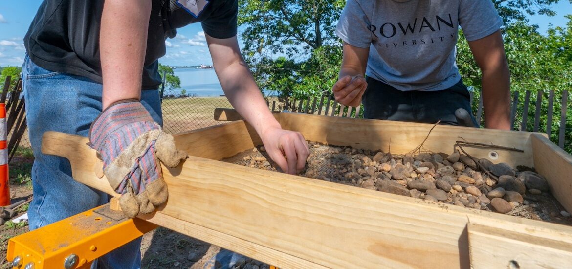 A close up of hands carefully sifting through soil at Red Bank Battlefield.