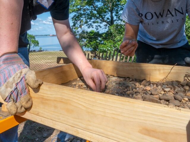 A close up of hands carefully sifting through soil at Red Bank Battlefield.