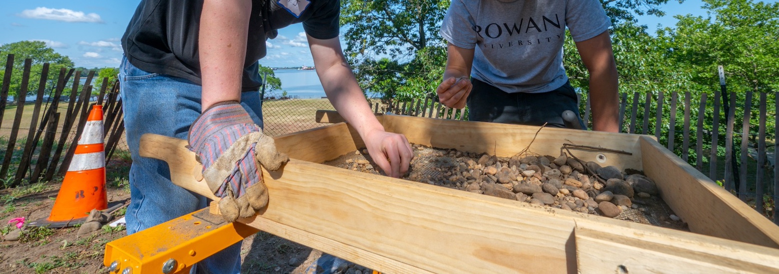 A close up of hands carefully sifting through soil at Red Bank Battlefield.