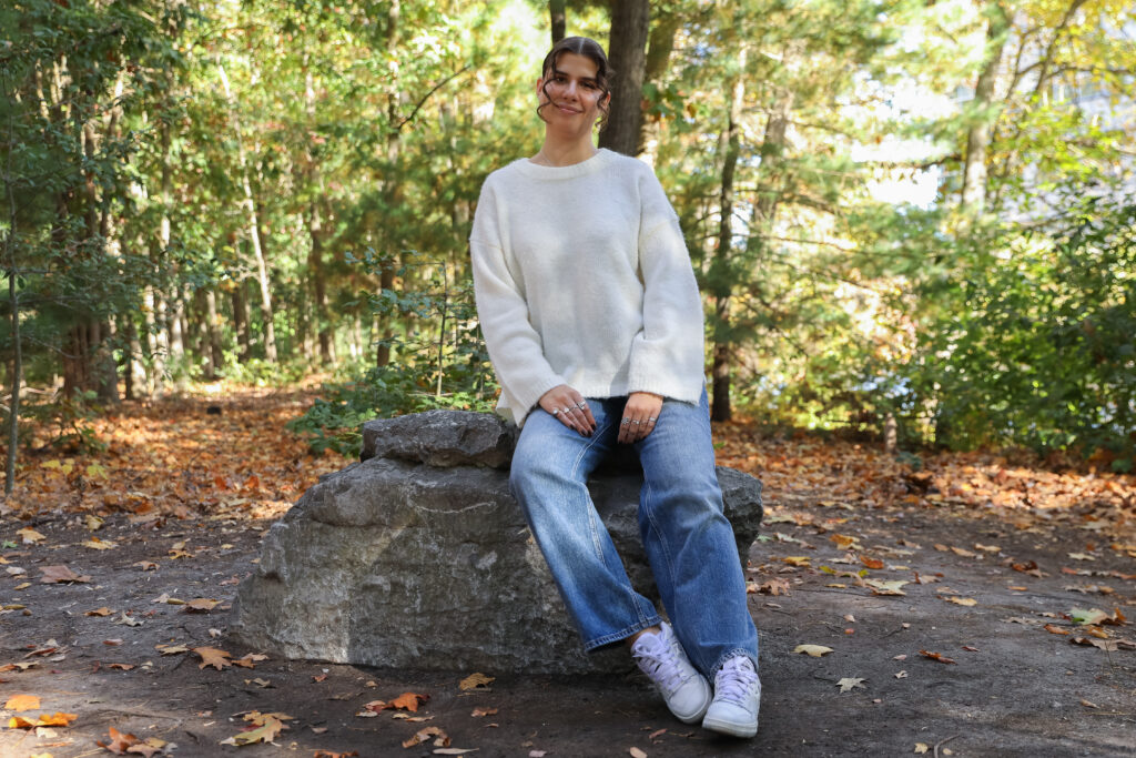 Daria Sapova sitting on a rock outside of the Engineering Hall at Rowan University. 