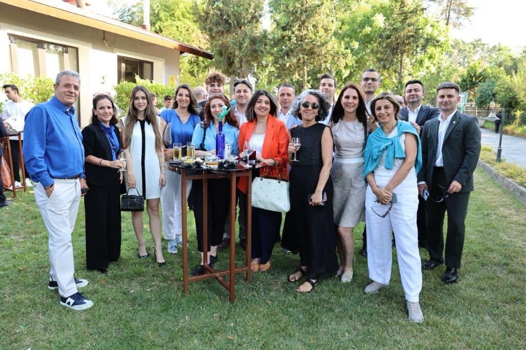 Tyler, his boss and his coworkers at a business party standing for a group photo of of 16 people. 