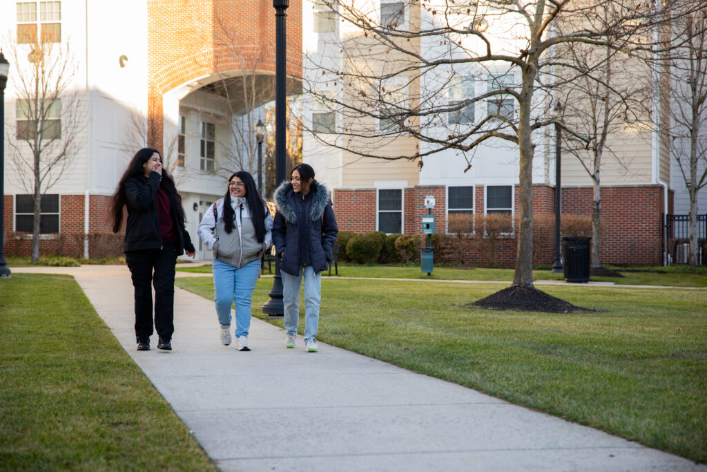 3 female students laughing by the Rowan Boulevard Apartments.