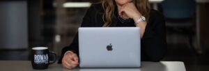 A close up of a professional in a suit working on a laptop, with a Rowan University mug next to them.