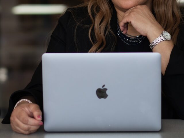 A close up of a professional in a suit working on a laptop, with a Rowan University mug next to them.