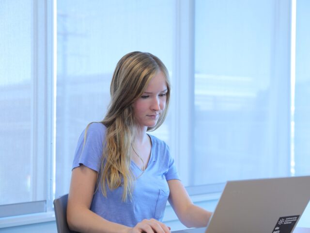 Student studying for an online healthcare administration degree on a laptop