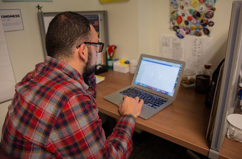 A Rowan University computer systems technology student works in his home office on a laptop. 