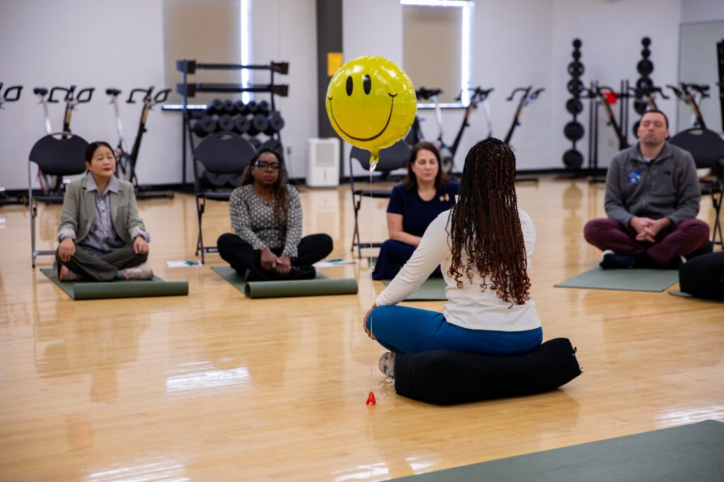 Health coach leading a group mindfulness session in a fitness & wellness center