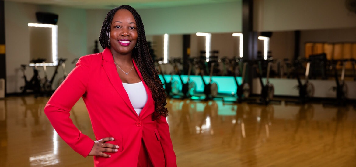 Confident health coach in a red suit standing in a fitness studio