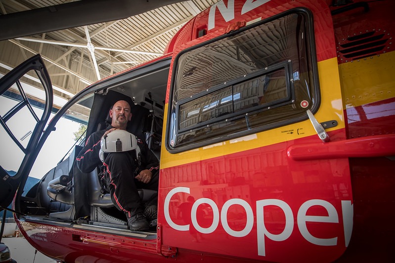 A Rowan University master of science in nursing student who is a flight nurse sits in his helicopter holding his helmet on his knee. 