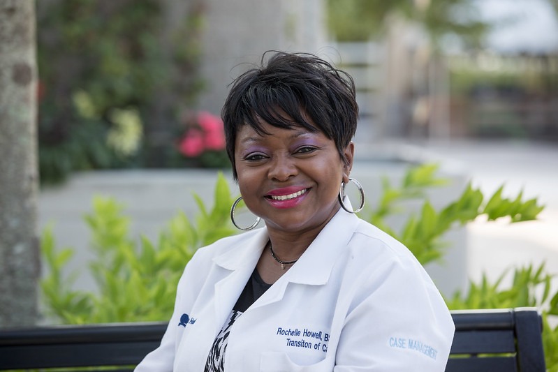 A Rowan University master of science in nursing student sits on a bench wearing a white coat. 